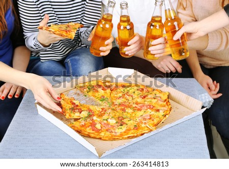 Friends hands with bottles of beer and pizza, close up