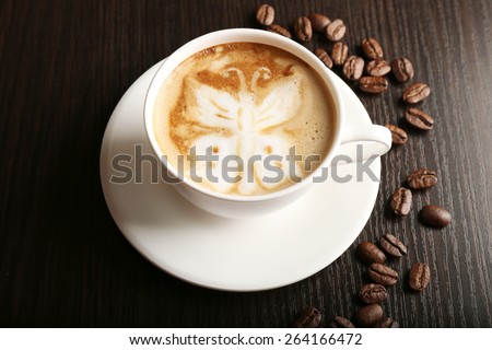 Cup of latte art coffee with grains on wooden background