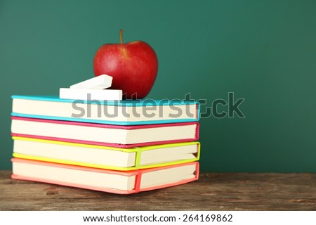 Books, apple and chalk on blackboard background