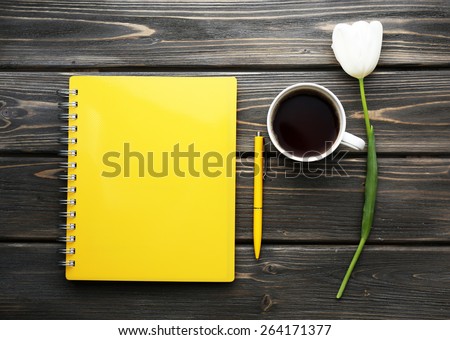 Notebook with cup of coffee and white tulip on wooden background Notebook with cup of coffee and white tulip on wooden background