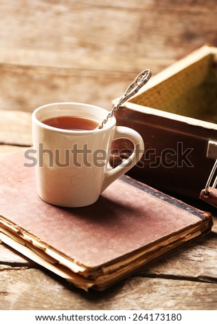 Old wooden suitcase with old books and tea cup on wooden background