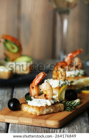Appetizer canape with shrimp and olives on cutting board on table close up