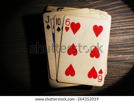 Stack of playing cards in light on wooden table, top view