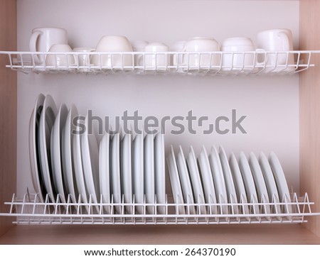 Clean dishes drying on metal dish rack on shelf