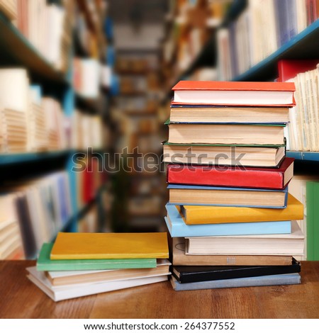 Stack of books on table on bookshelves background