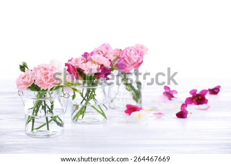 Beautiful spring flowers in glass bottles isolated on white