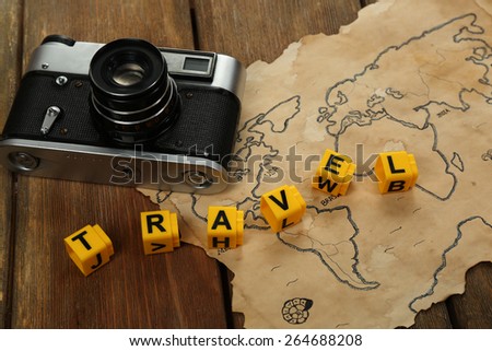 Retro camera on world map with word Travel on wooden table background