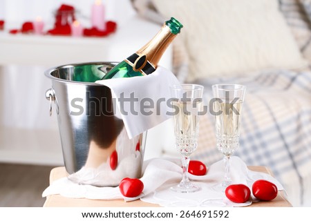 Champagne bottle in bucket,  glasses and rose petals for celebrating Valentines Day