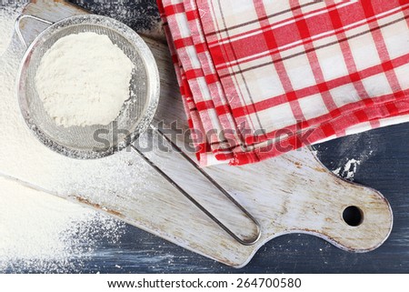 Sifting flour through sieve on cutting board and on wooden table, top view