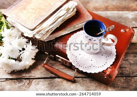 Old wooden suitcase with old books and flowers on wooden background