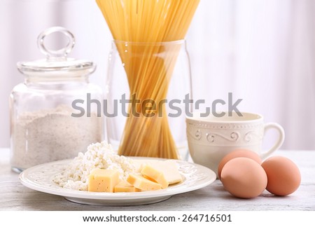 Pasta with diary products, flour and eggs on wooden table on curtain background