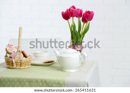 Tea set with flowers on table, on light background