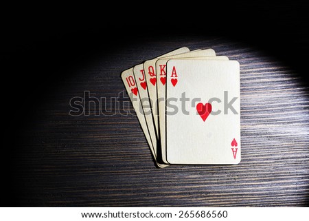 Playing cards in light on wooden table, top view