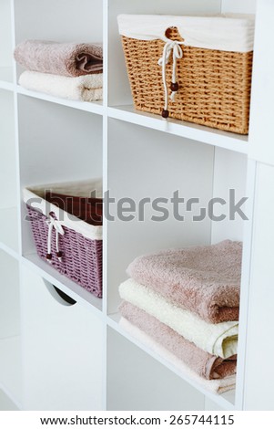 Pile of towels with wicker baskets on shelves of rack background