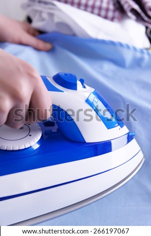 Female hand ironing clothes on ironing board, closeup