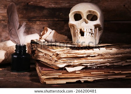 Still life with human skull, retro book and quill on wooden table, closeup