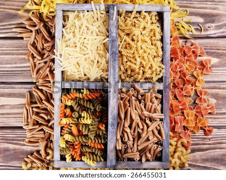Different types of pasta in box on wooden background