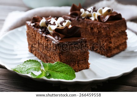 Tasty pieces of chocolate cake with mint on wooden table background