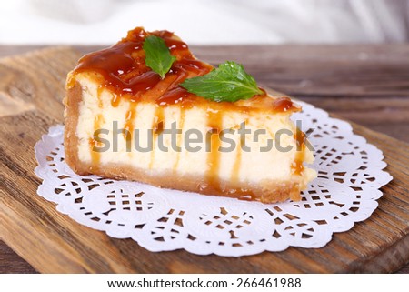 Cheese cake on paper napkin on cutting board on wooden table on light background