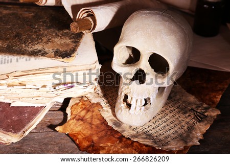 Still life with human skull and retro book on wooden table, closeup