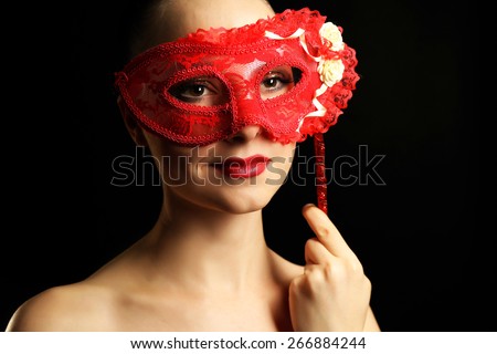 Portrait of beautiful woman with fancy glitter makeup and masquerade mask on dark background