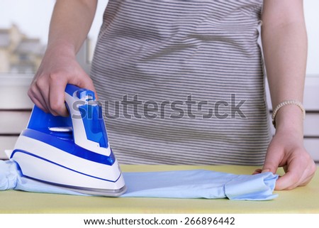Woman ironing clothes on ironing board, closeup