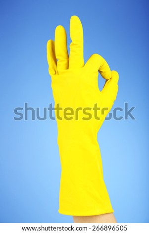 Rubber glove on hand, on blue background