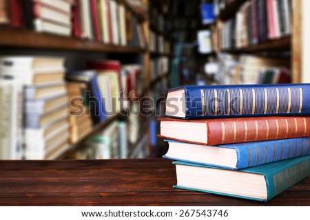 Stack of books on table on bookshelves background