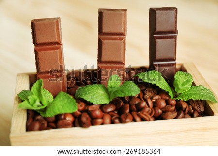 Still life with set of chocolate in wooden box of coffee grains, closeup
