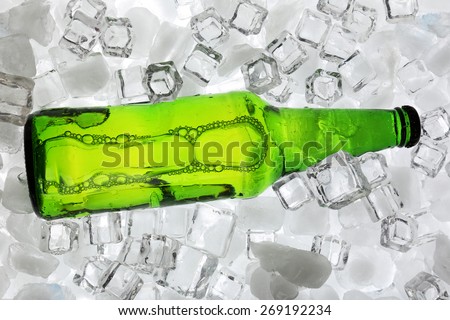 Glass bottle of beer on ice cubes background
