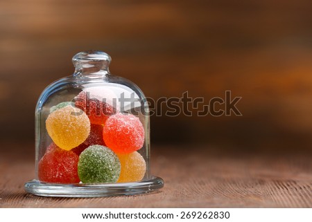 Colorful candies in jar on table on wooden background