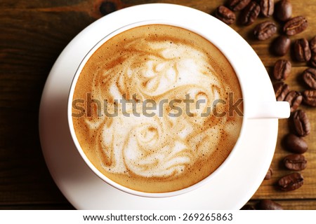 Cup of coffee latte art with grains on wooden table, top view