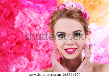 Portrait of young woman with flowers in hair on bright pink background