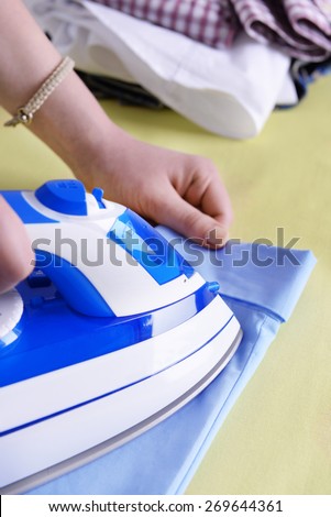 Woman ironing clothes on ironing board, closeup