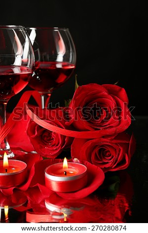 Composition with red wine in glasses, red rose and decorative heart on dark background