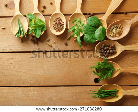 Wooden spoons with fresh herbs and spices on wooden background