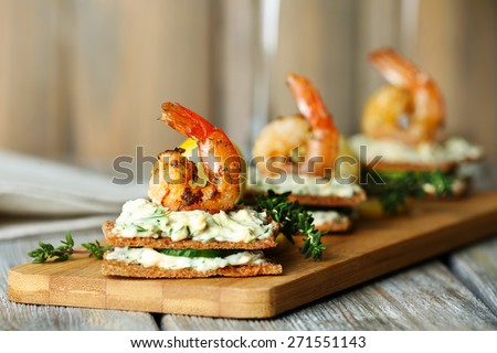 Appetizer canape with shrimp and cucumber on plate on table close up