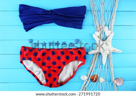 Sea still life with swimsuit on wooden table, top view