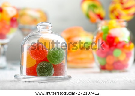 Colorful candies in jars on table on light background background