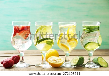 Glasses of different home made freshness healthy vitamin-fortified water on wooden table