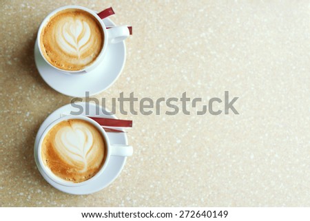 Cups of cappuccino with heart on foam on table in cafe