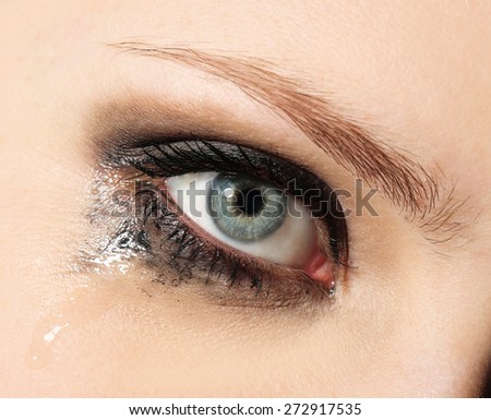 Eye of young woman with tear drop close up