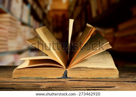 Old book on wooden table on bookshelves background