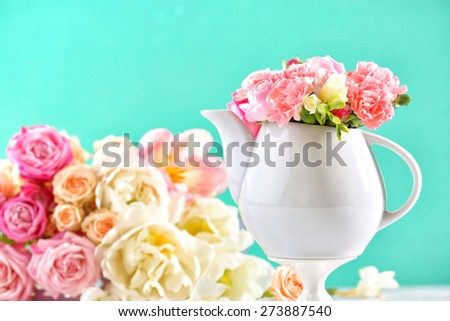 Composition beautiful spring flowers in teapot on light blue background