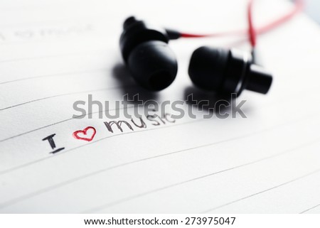 Earphones on notebook with text I Love Music, closeup
