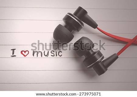 Earphones on notebook with text I Love Music, closeup