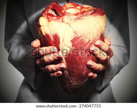Woman holding raw animal heart close up
