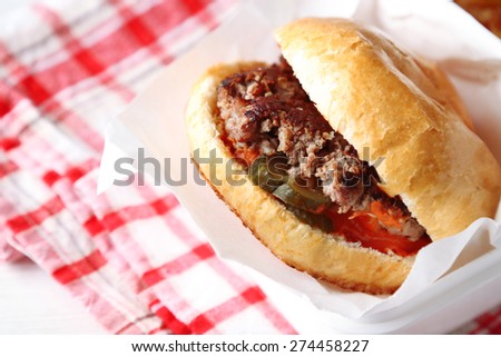 Tasty burger on paper napkin, on wooden table background, close-up. Unhealthy food concept