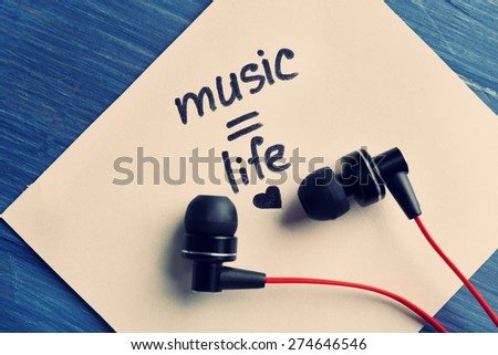 Earphones with text Music - life on sticker on wooden table, closeup
