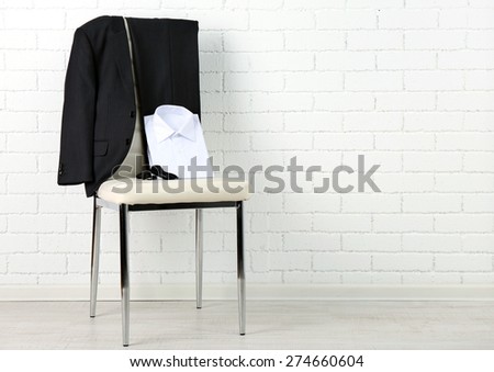 School clothes for boy on chair, on white wall background